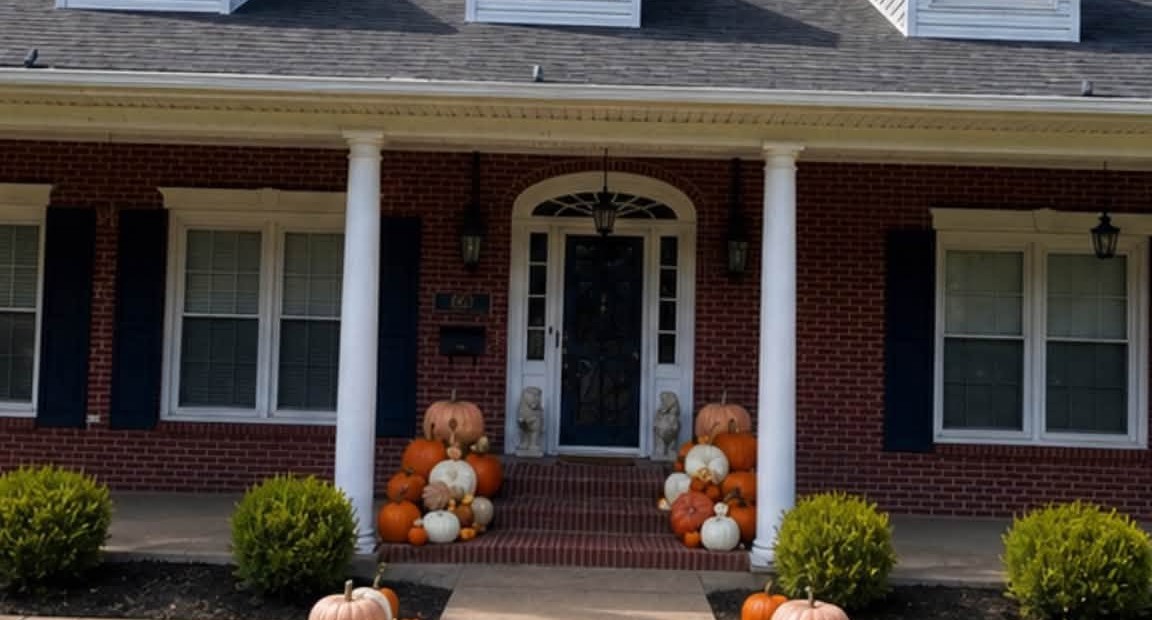 Grand columned brick home with layered pumpkin displays flanking the front steps