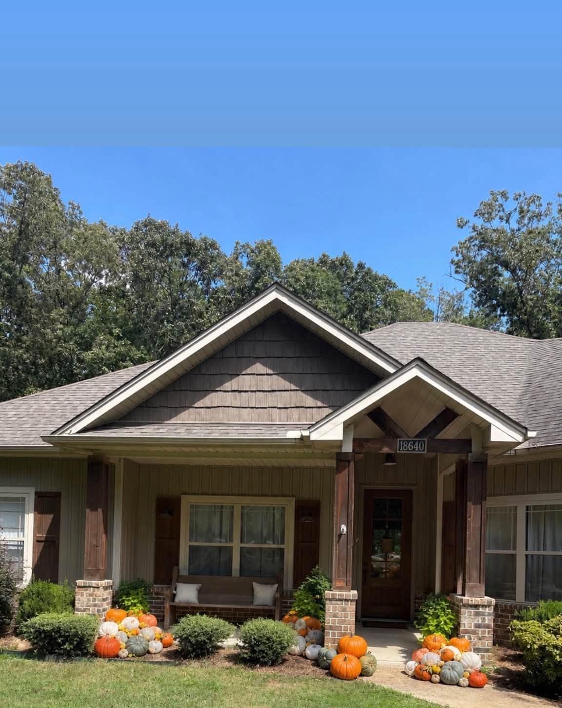 Craftsman-style home with mums and pumpkins clustered at the porch steps